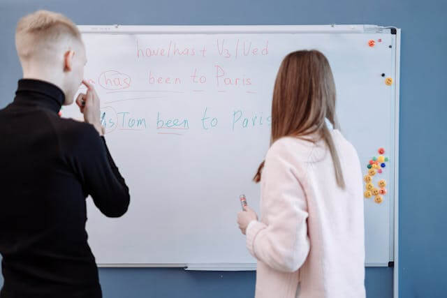 An experienced instructor explaining grammar on a whiteboard.